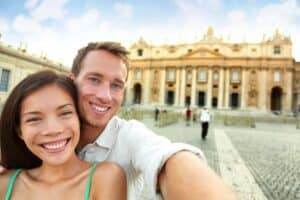Vibrant couple taking selfie in front of historic Italian architecture, showcasing Italy travel, culture, and sightseeing experiences at a famous landmark.