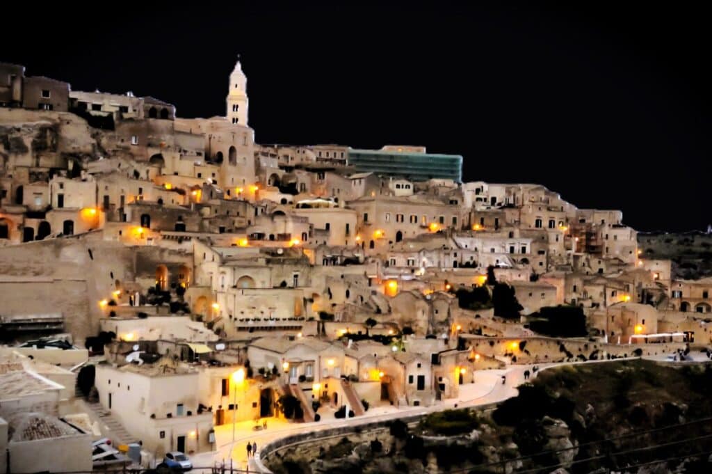 Ancient hillside town illuminated at night, Italy, historic architecture, nighttime cityscape, Curio Italia travel destination, cultural heritage, scenic views, Mediterranean, Italy tourism, night photography.