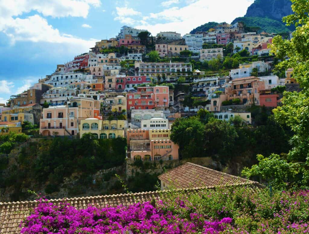 Vibrant hillside village in Italy featuring colorful houses, lush greenery, and scenic mountain views, showcasing the charm and beauty of Italian coastal towns.