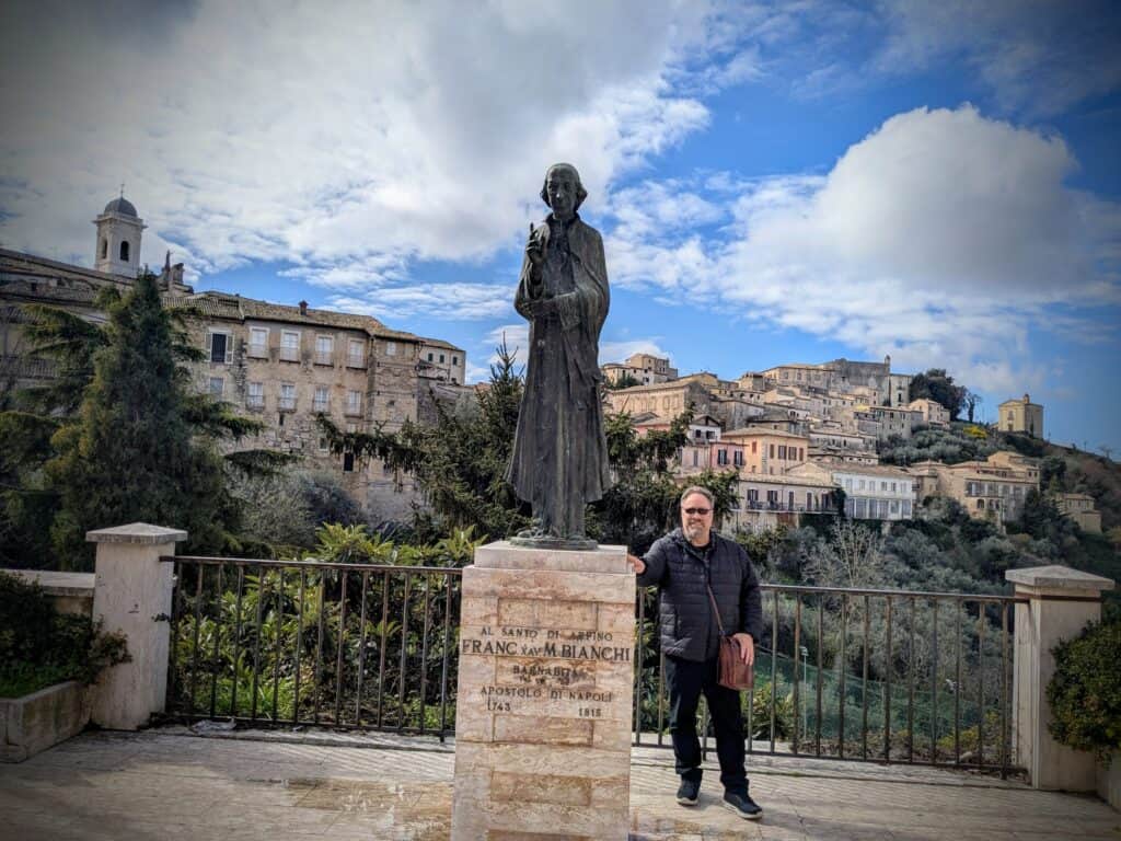 Statue of Francesco Maria Bianchi in an outdoor setting with historic buildings and a blue sky in the background, representing Italian cultural heritage.