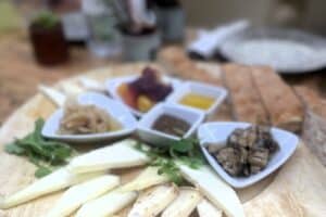Traditional Italian antipasto platter with cheeses, cured meats, and condiments on a wooden board, showcasing Italian culinary culture.
