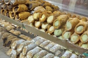 Variety of traditional Italian cannoli and pastries displayed in a bakery showcase, showcasing authentic Italian desserts.