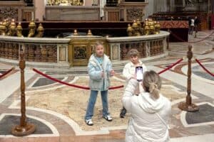 Family taking a photo inside Vatican Museum with ornate decorations and marble flooring.
